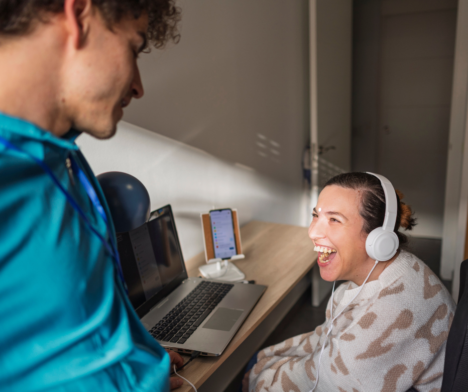 Disability support worker assisting a woman with headphones at Aspire Hub Australia